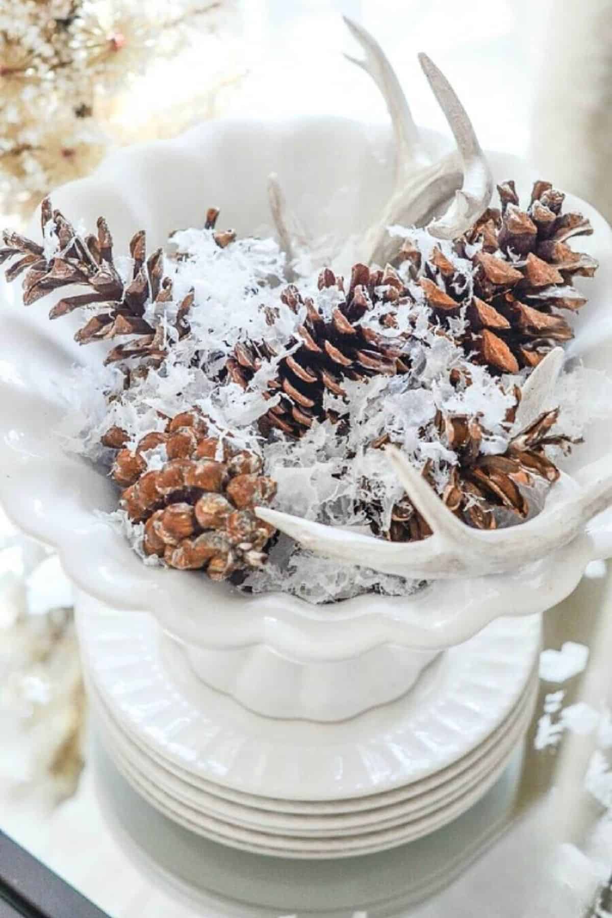 pinecones with faux snow in a white pedestal bowl