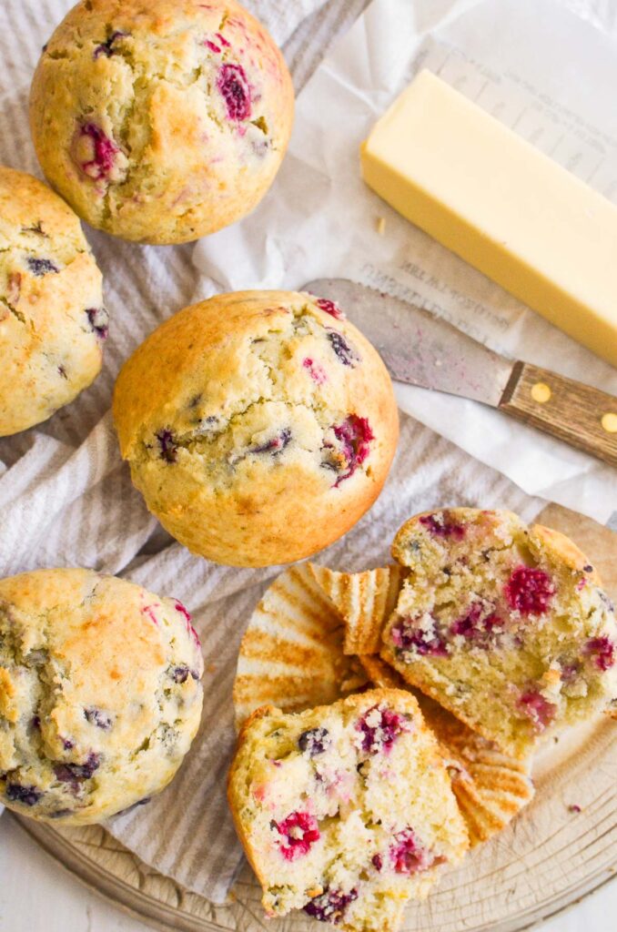 mixed berry muffins. some cut in half and the papers off of them, on a wooden round