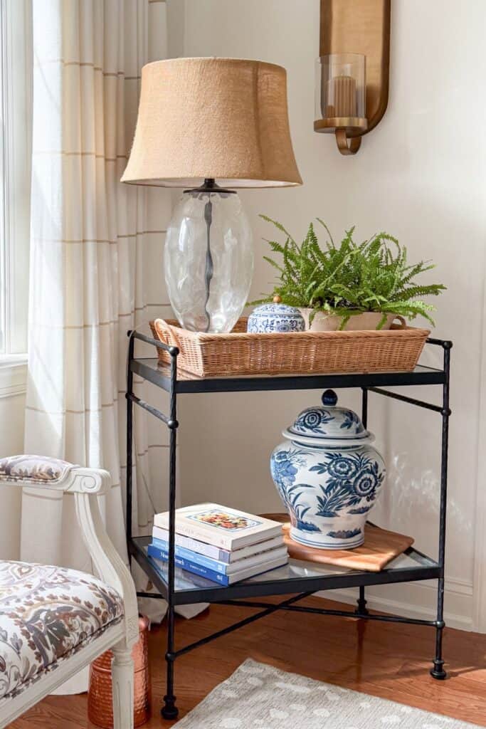 Wicker tray with a lamp, fern, and blue and white ginger jar styled on a black accent table for budget friendly home decorating.