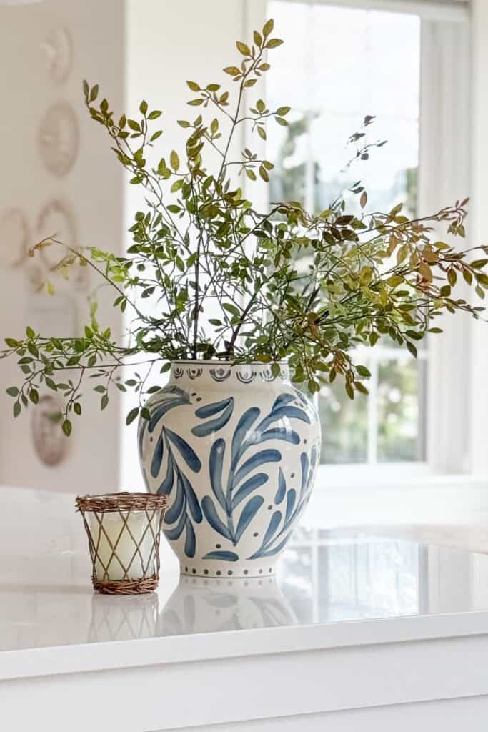 Blue and white vase filled with greenery on a white kitchen island for budget friendly home decorating.