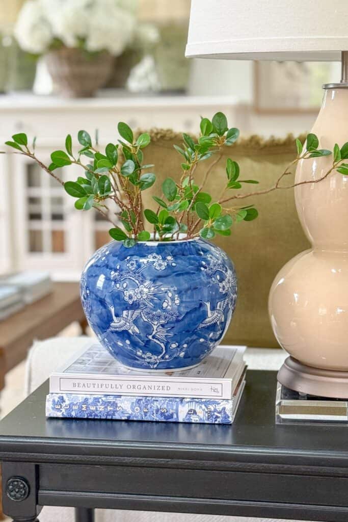 a chinoiserie vase on blue and white books on a black end table