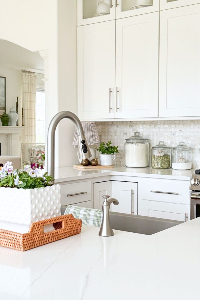 spring kitchen decorating ideas with sink area styling, glass canisters, and small plant on counter