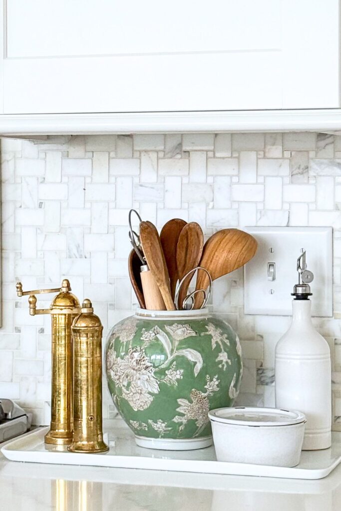 spring kitchen decorating ideas with tray styling by stove, wooden utensils in green ginger jar, oils and salt