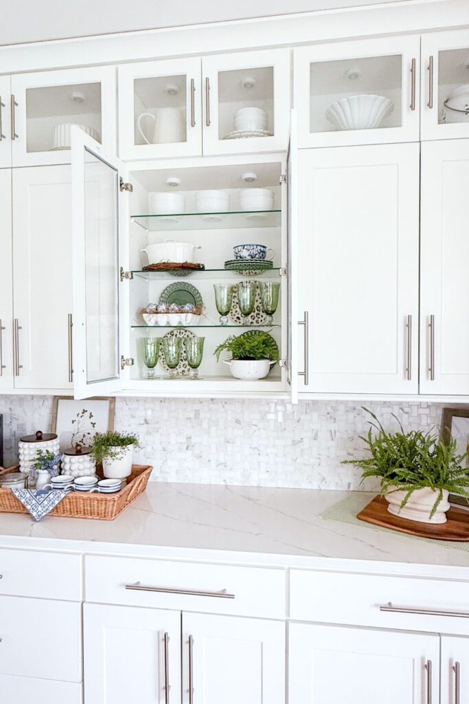 spring kitchen with glass front cabinets styled with dishes and greenery and decorated countertops