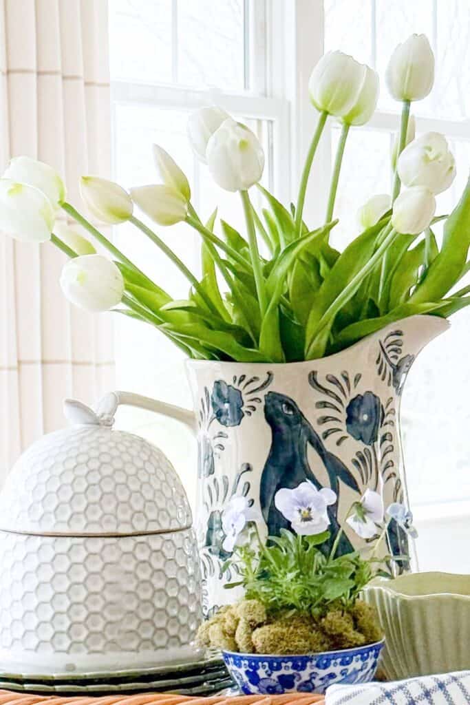 spring kitchen decor with blue and white bowl of pansies, tulips in pitcher, and tray styling on counter