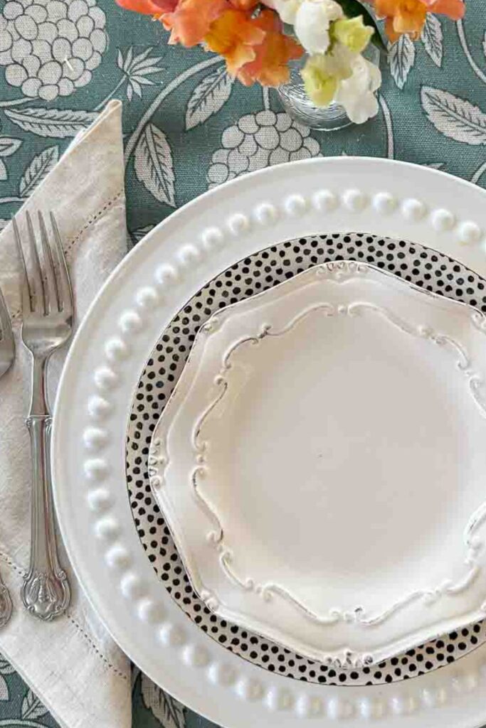 BLACK AND WHITE PLACE SETTING ON A GEEN AND BEIGE TABLECLOTH