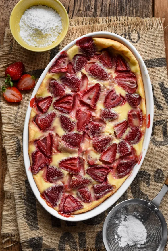 strawberry flaugnarde in a white oval baking dish