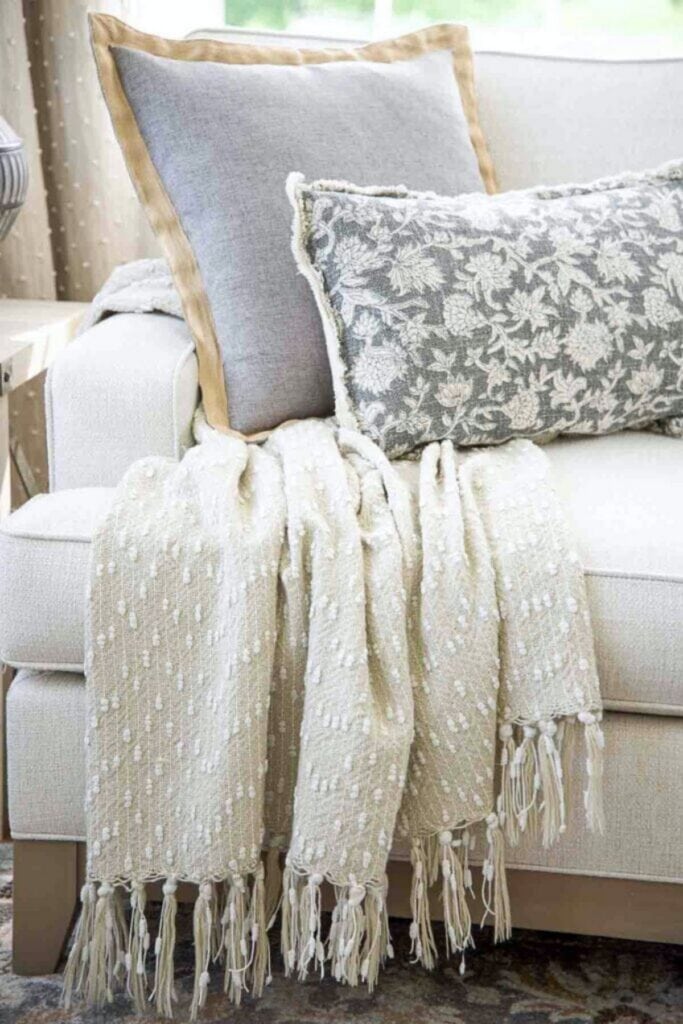 cotton throw blanket and two decorative pillows on a sofa