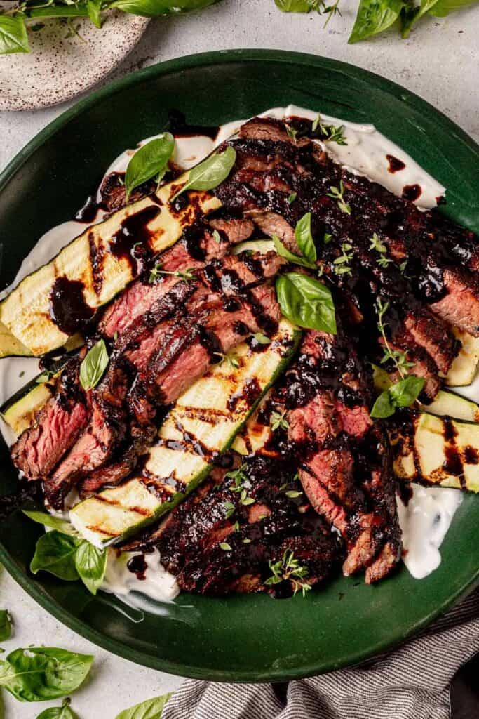 plate of sliced grilled flank steak with grilled zucchini