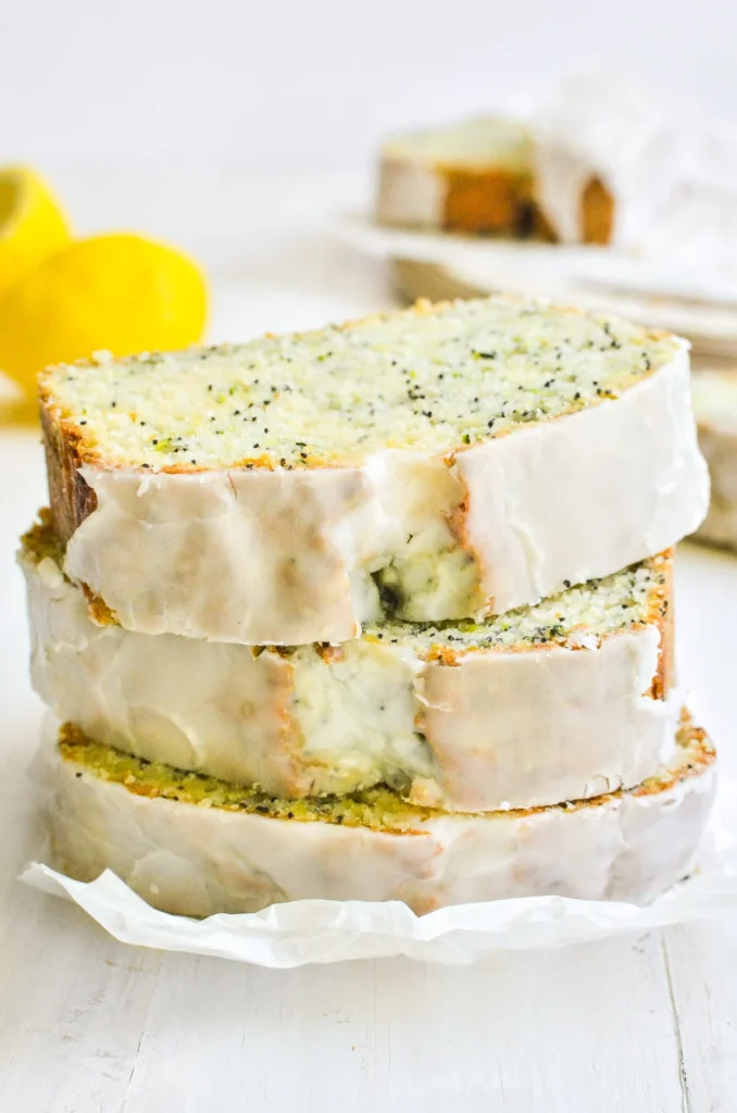 slices of lemon zucchini poppyseed bread with the glazed tops facing forward on plate