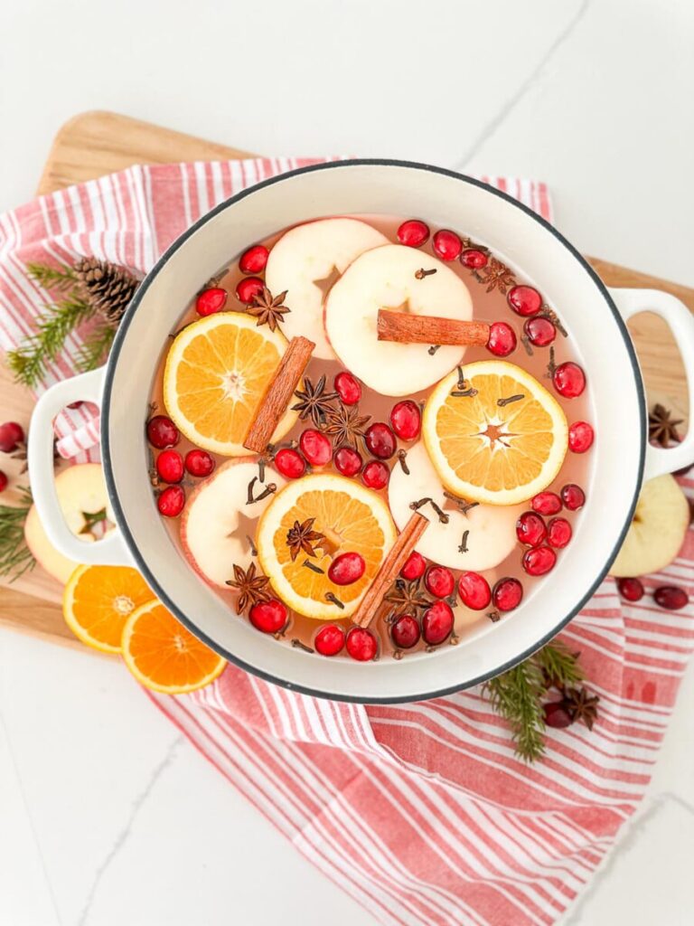 A pot of Christmas mulled cider with oranges, apples, cranberries, cinnamon sticks, cloves, and star anise.