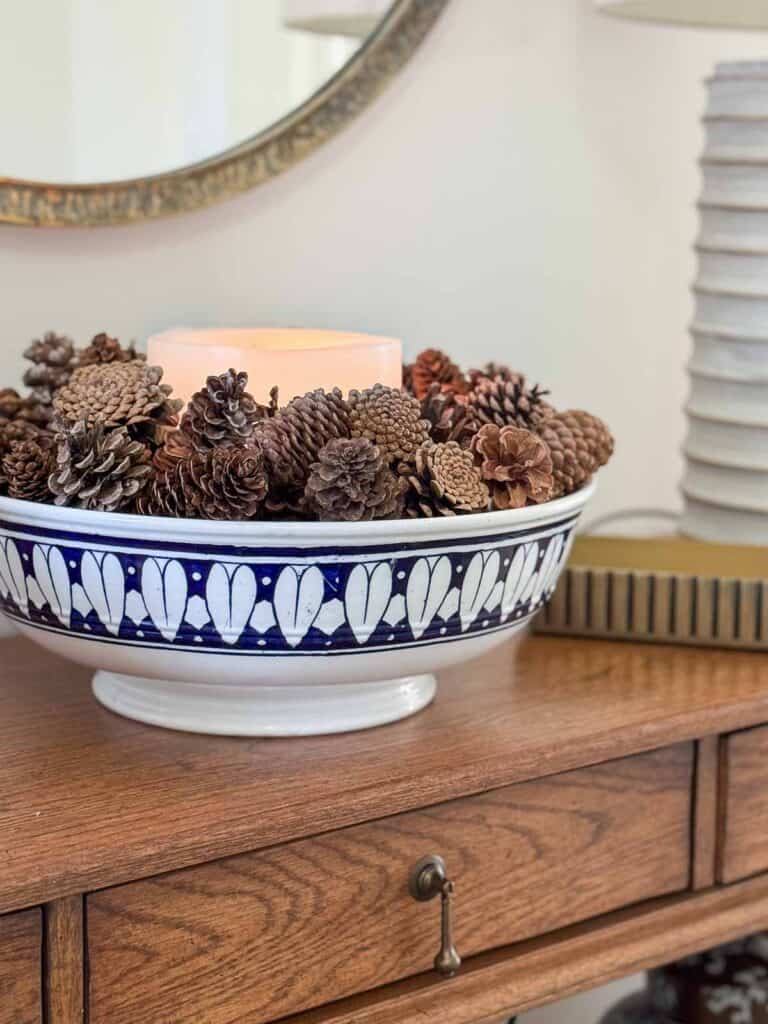 scented candle in the center of a large bowl of pinecones