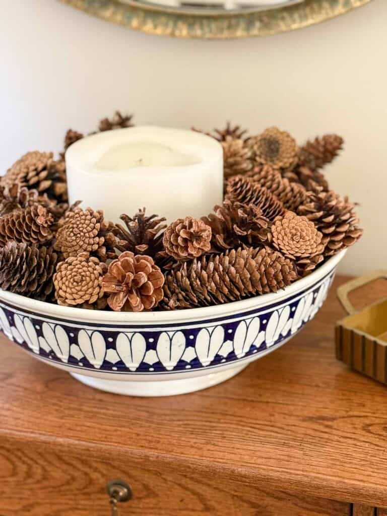large wide bowl with a candle and pinecones in it