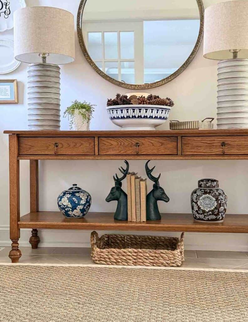 bottom shelf of a foyer decorated for winter with a woven tray for shoes.