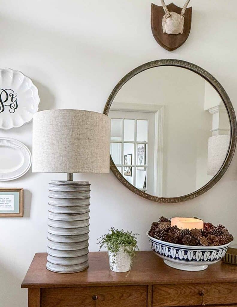 round mirror above a foyer table decorated for winter for winter