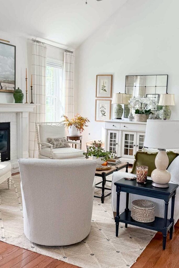 Living room fireplace decorated with large artwork, green vases, brass candlesticks, and surrounding layered details for a balanced look.