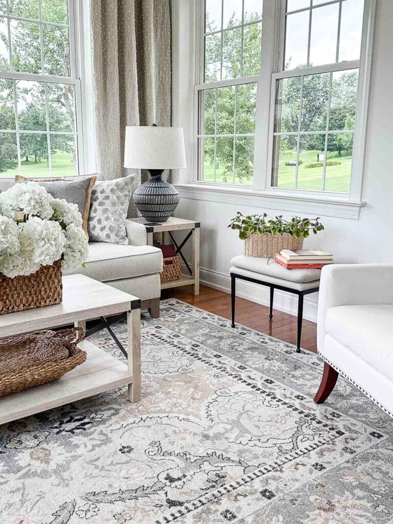corner in a sunroom with an upholstered bench and a basket with a plant.