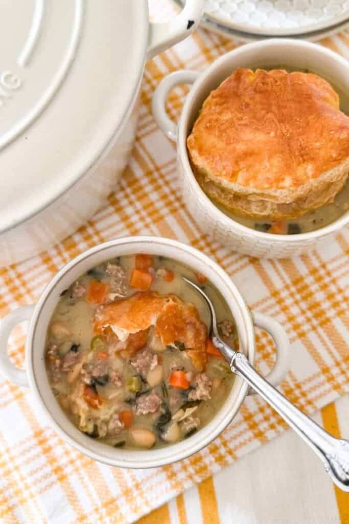 two bowls of soup on a yellow tea towel and a white pot filled with soup in the background