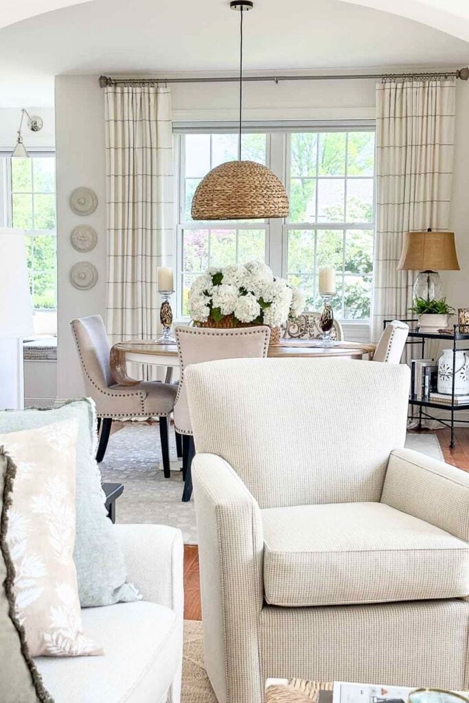 NEUTRAL COLOR CHAIR IN A LVING ROOM LOOKING INTO THE DINING ROOM
