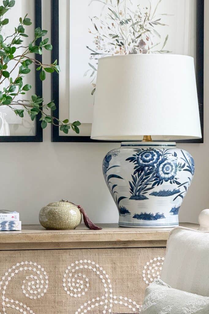 blue and white chinoiserie lamp styled with a small green accessory and green branches on a neutral console table