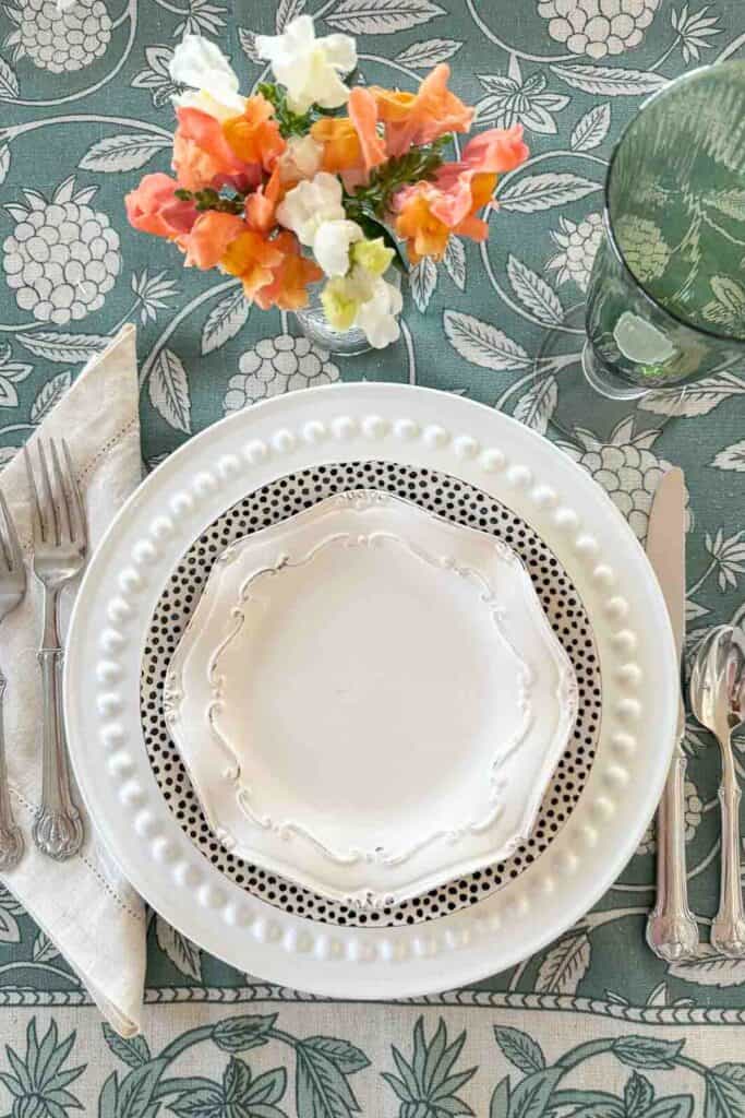 place setting on a green and ivory tablecloth
