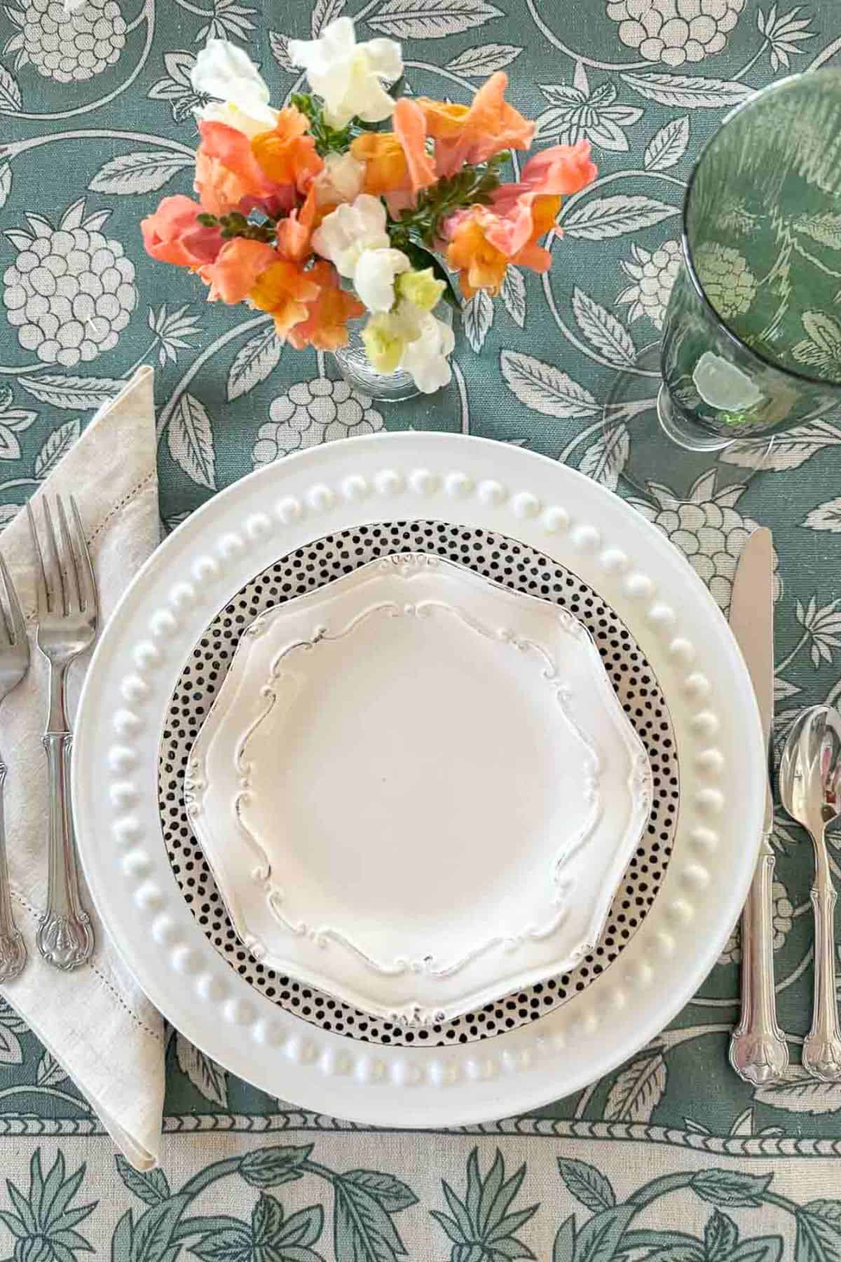 place setting on a green and ivory tablecloth