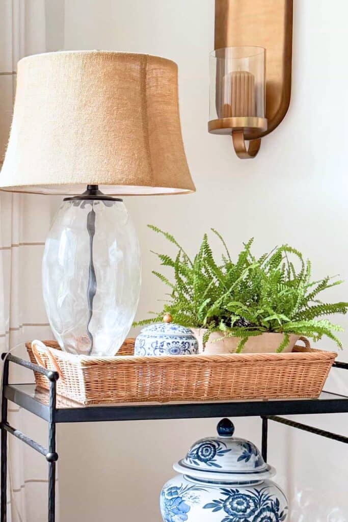 Bar cart styled with neutral lamp, green fern, and blue and white ginger jar showing the rule of three in color