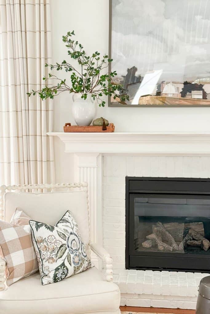 Single vase of greenery on a woven tray on a mantel, a simple standalone decor moment