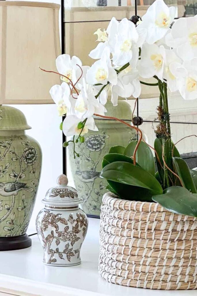 console table styled with lamp, orchid plant, woven basket, and decorative accessories