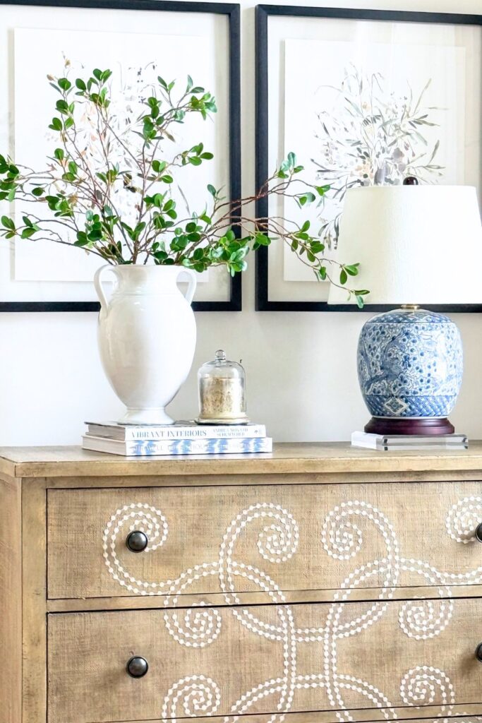 clear riser under a lamp and books acting as risers and topped with an urn and candle.