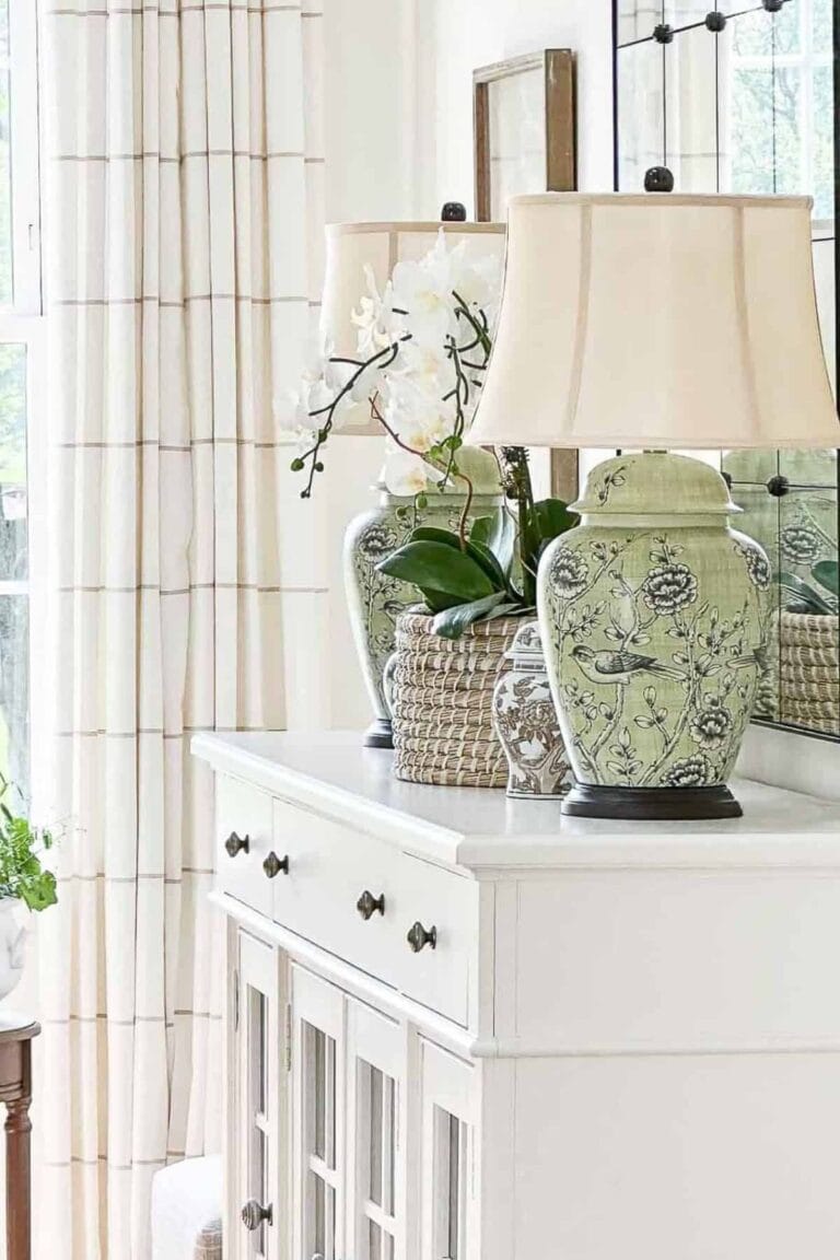 green ginger jar lamps on a white buffet with an orchid plant