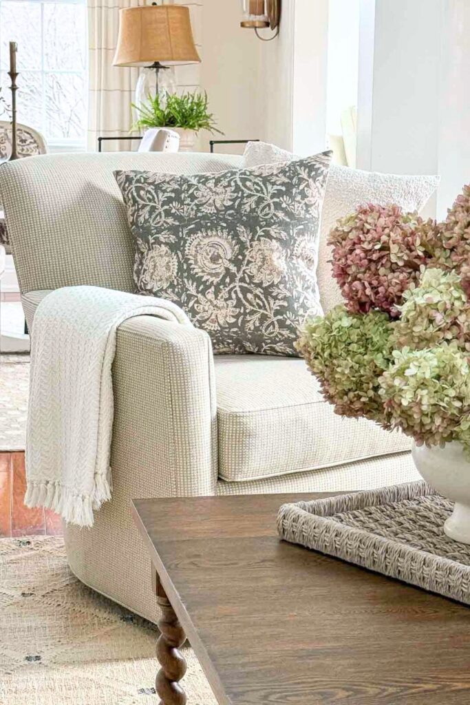 neutral chair styled with throw blanket and decorative pillows in a cozy living room