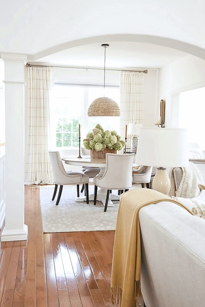 neutral dining room with area rug, table lamp, and hydrangea centerpiece