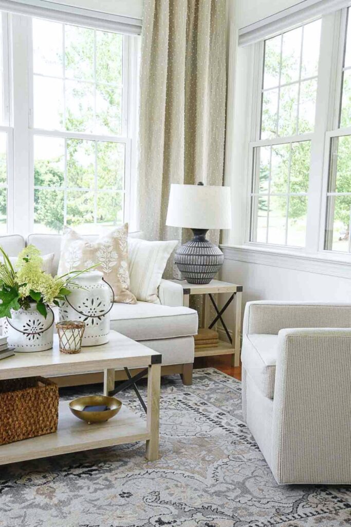 neutral living room with lamp, area rug, pillows, and styled coffee table accessories