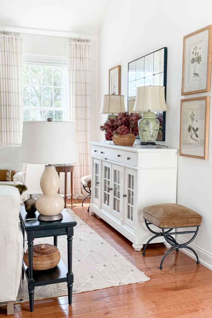 neutral living room with lamps, area rug, console table, and layered home decor accessories