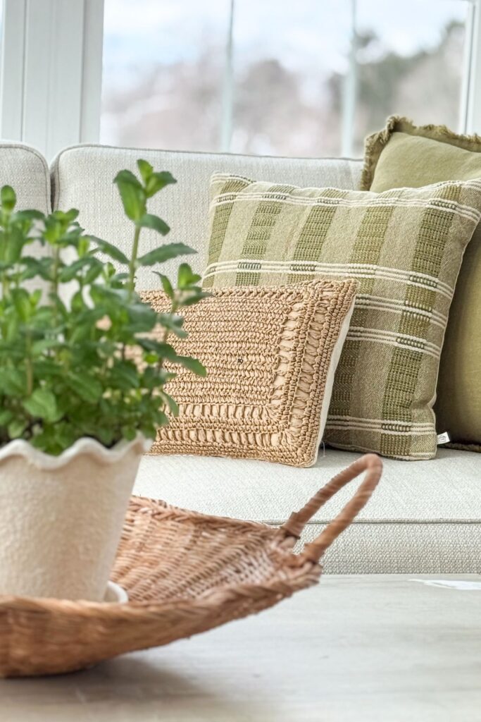 neutral sofa styled with green and tan throw pillows and woven textures