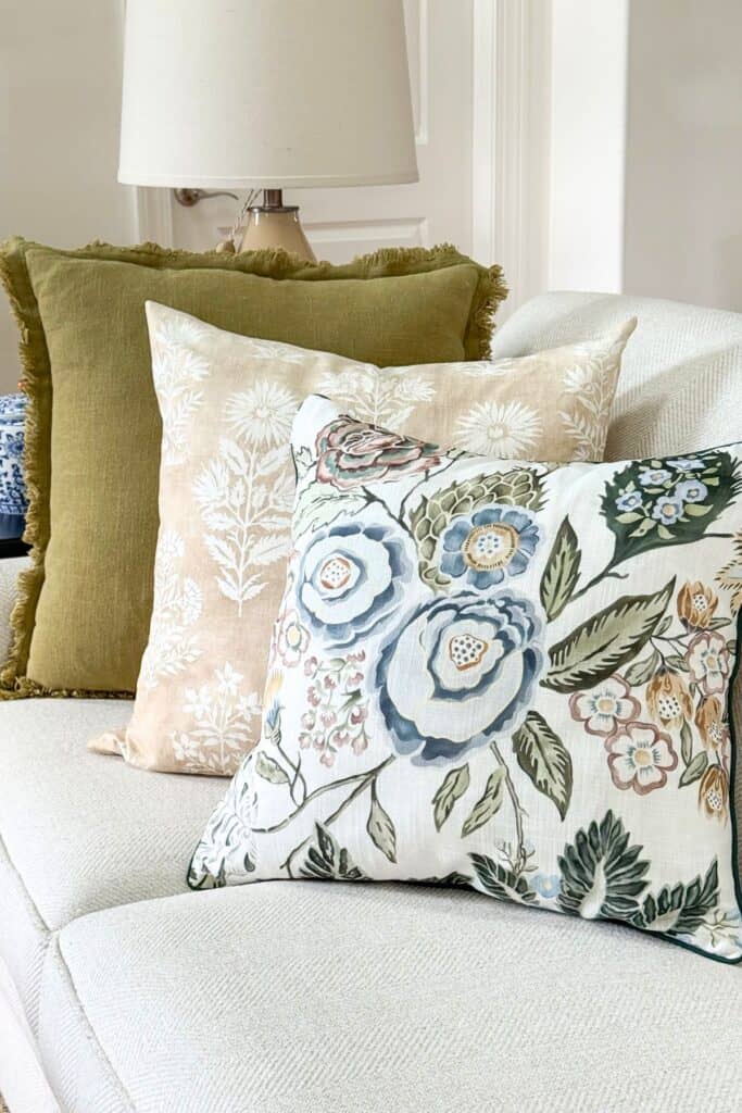 a trio of green, blue and white pillows on a sofa