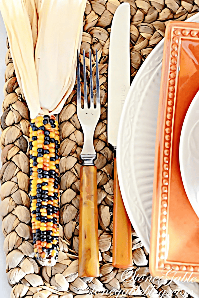 mini Indian corn sitting next to a fork on a place setting for Thanksgiving.