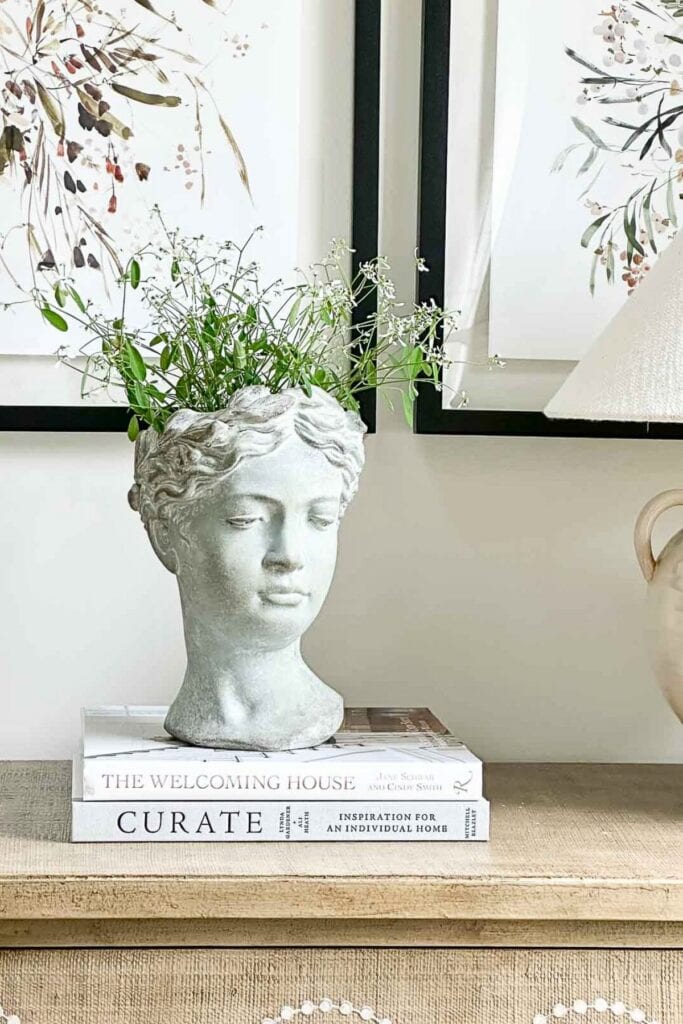 Vintage bust planter with greenery on a rustic wooden table.