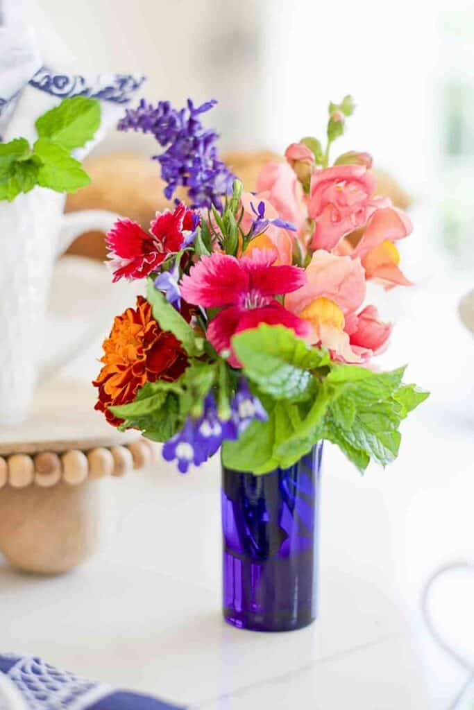 Colorful bouquet of mixed flowers in a blue glass vase representing what does mercy mean in the bible