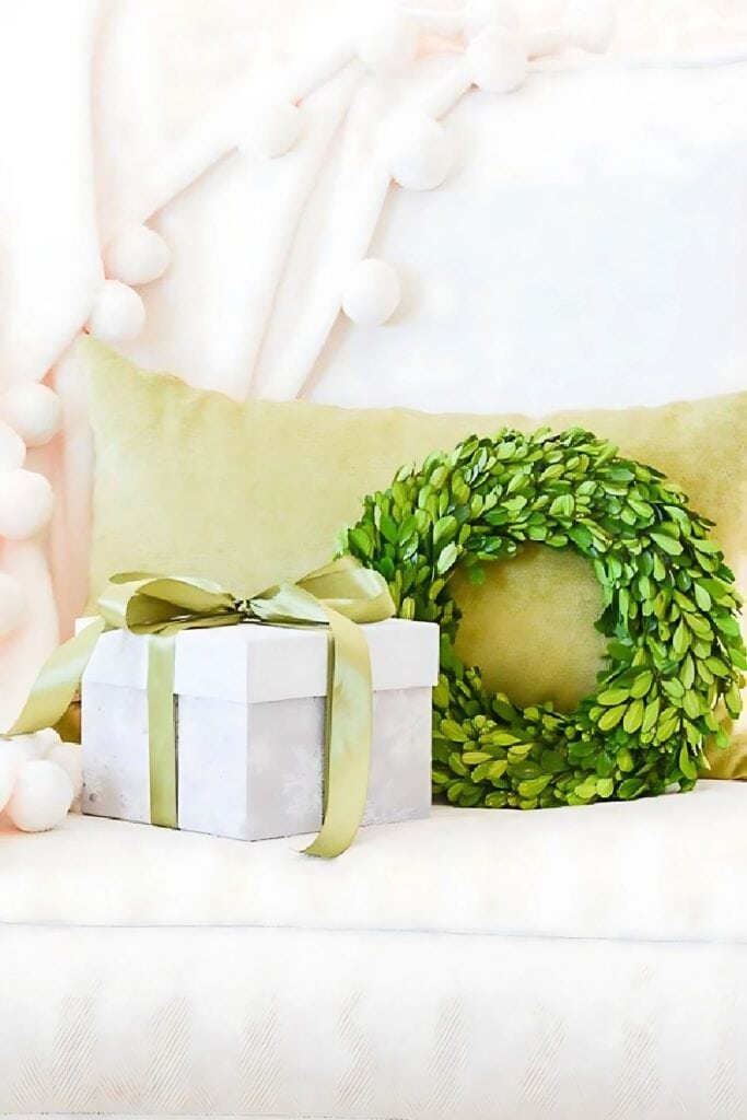 a white chair with boxwood wreath and a Christmas gift