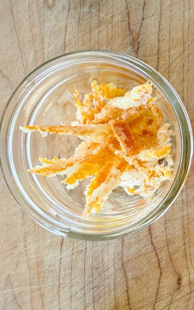 sugar coated candied orange peel strips in a glass bowl, overhead view