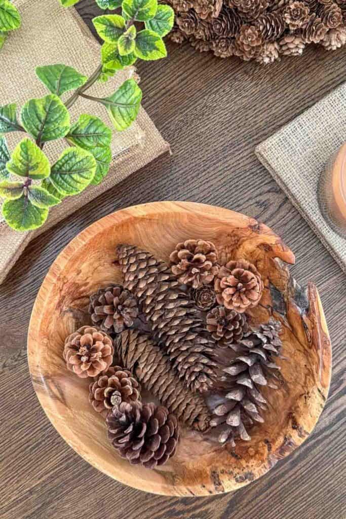 wooden bowl of pinecones and other decor on a coffee table