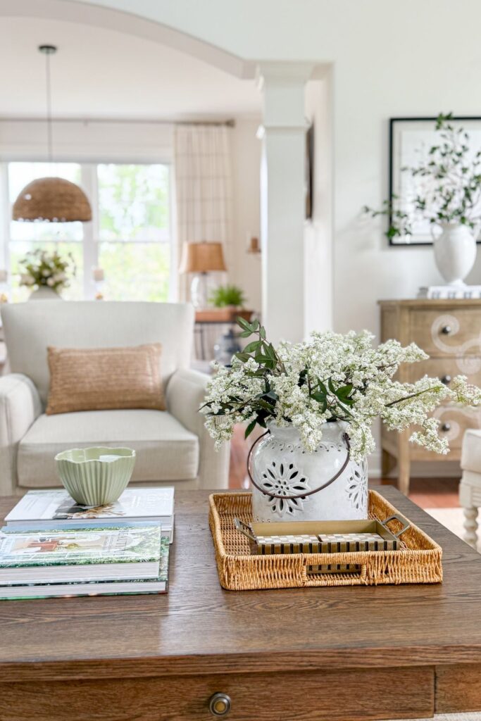 Semi open concept living room with arched doorway, wicker tray, and white ceramic pitcher filled with flowers