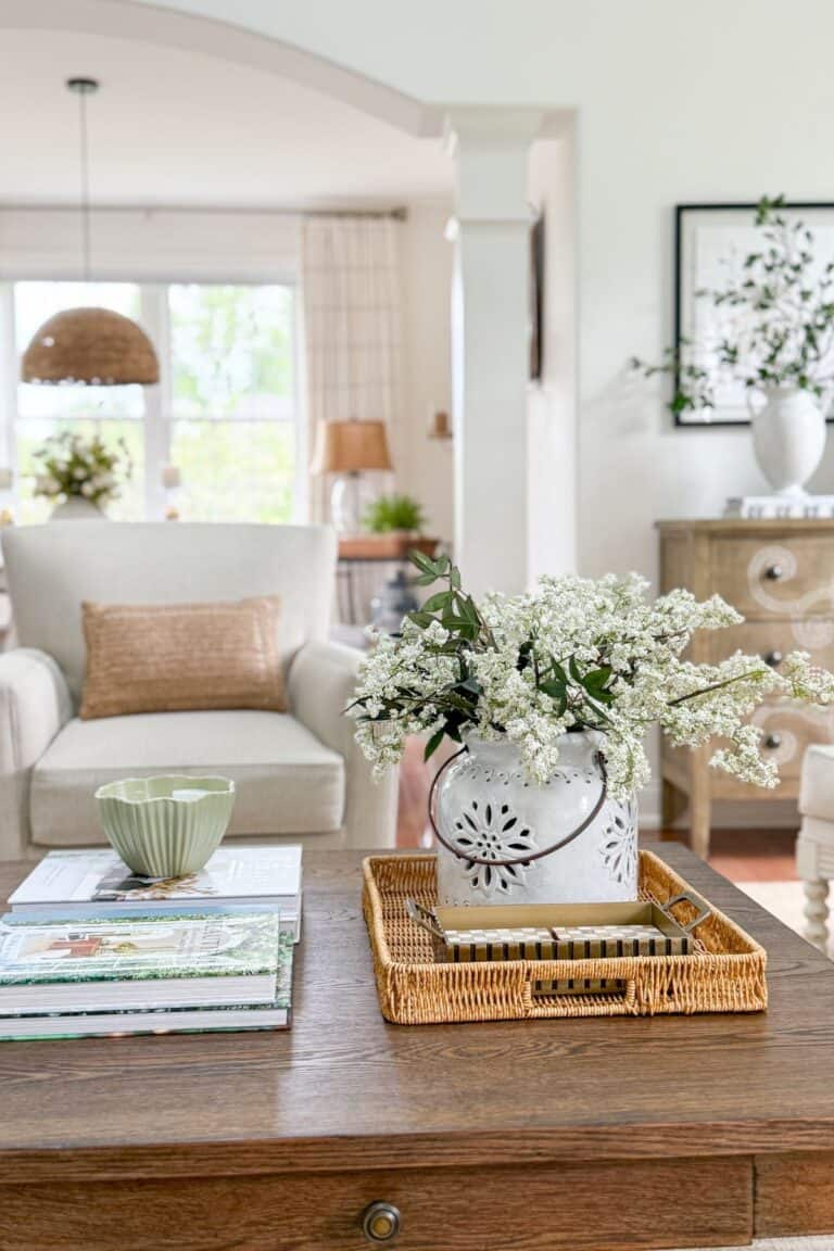 Semi open concept living room with arched doorway, wicker tray, and white ceramic pitcher filled with flowers