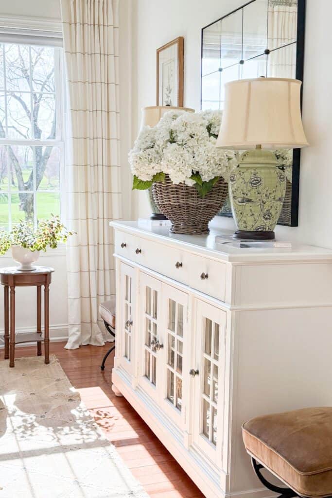 white buffet with a wicker vase filled with hydrangeas in the living room