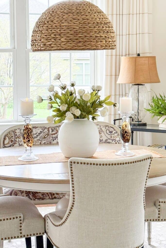 white vase filled with white flowers on a dining room table
