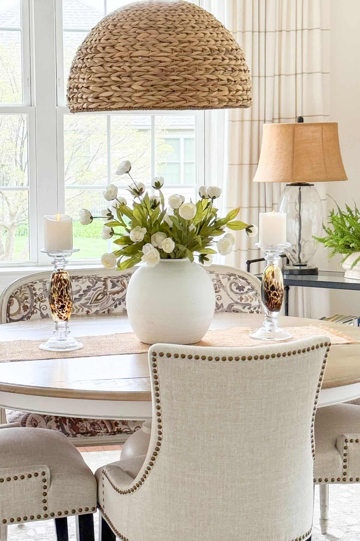 round vase of faux white flowers on a dining room table