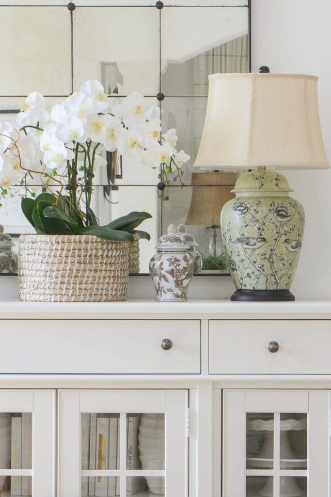 FAUX ORCHIDS and green lamp on a white buffet