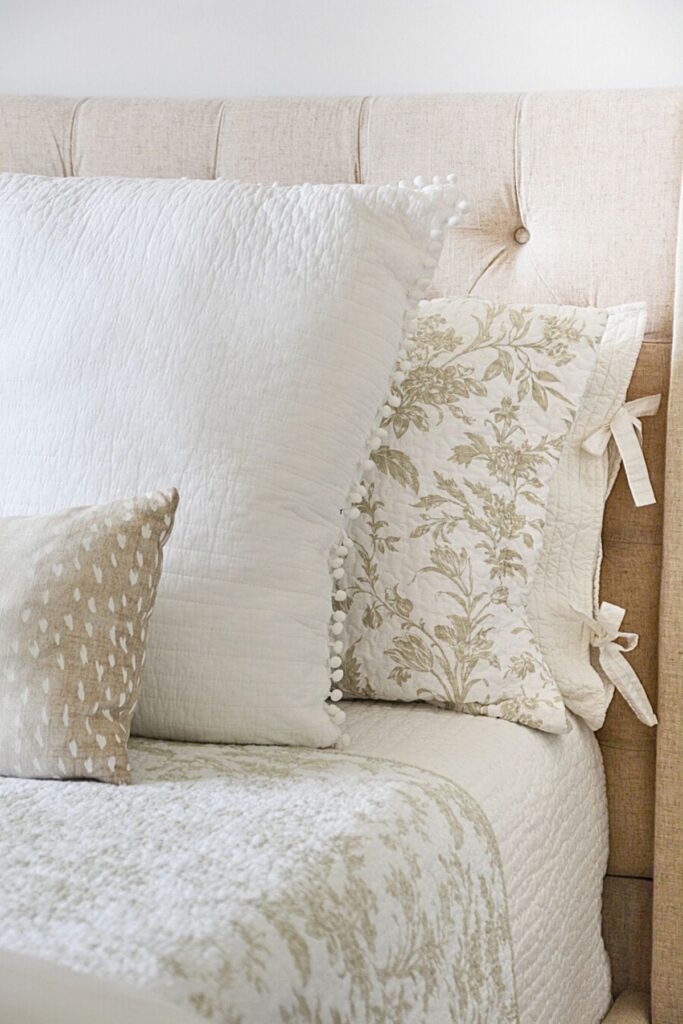 neutral spring pillows and light bedding layered on a bed creating a soft and simple look after Easter